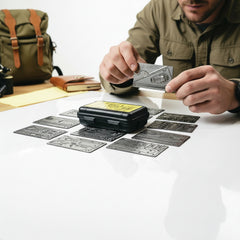 lifestyle photograph of the survival card bundle staged with outdoor gear and natural terrain.
