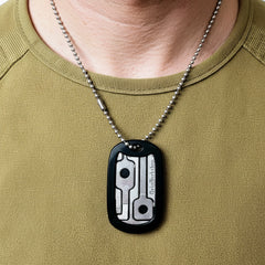 Close up of escape dog tag showing removable handcuff key, shim, and file.