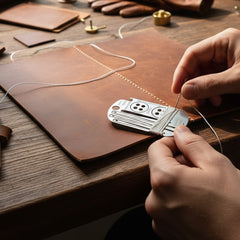 Travel sewing kit dog tag necklace with sewing needles, seam ripper, and buttons arranged in compact wearable design